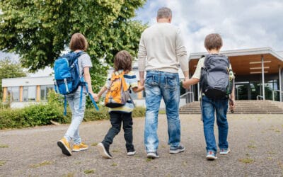Father walking 3 children to school in morning.