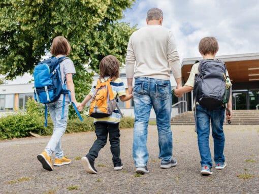 Father walking 3 children to school in morning.