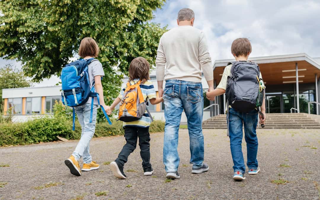Father walking 3 children to school in morning.