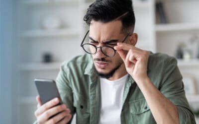 Middle-age man with aging eyes squinting while reading phone screen.