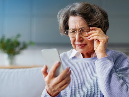 Senior woman in Pittsburgh having trouble reading phone screen potential eye disease warning sign.