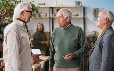 Three senior adult men socializing in Pittsburgh discussing signs of potential hearing loss.