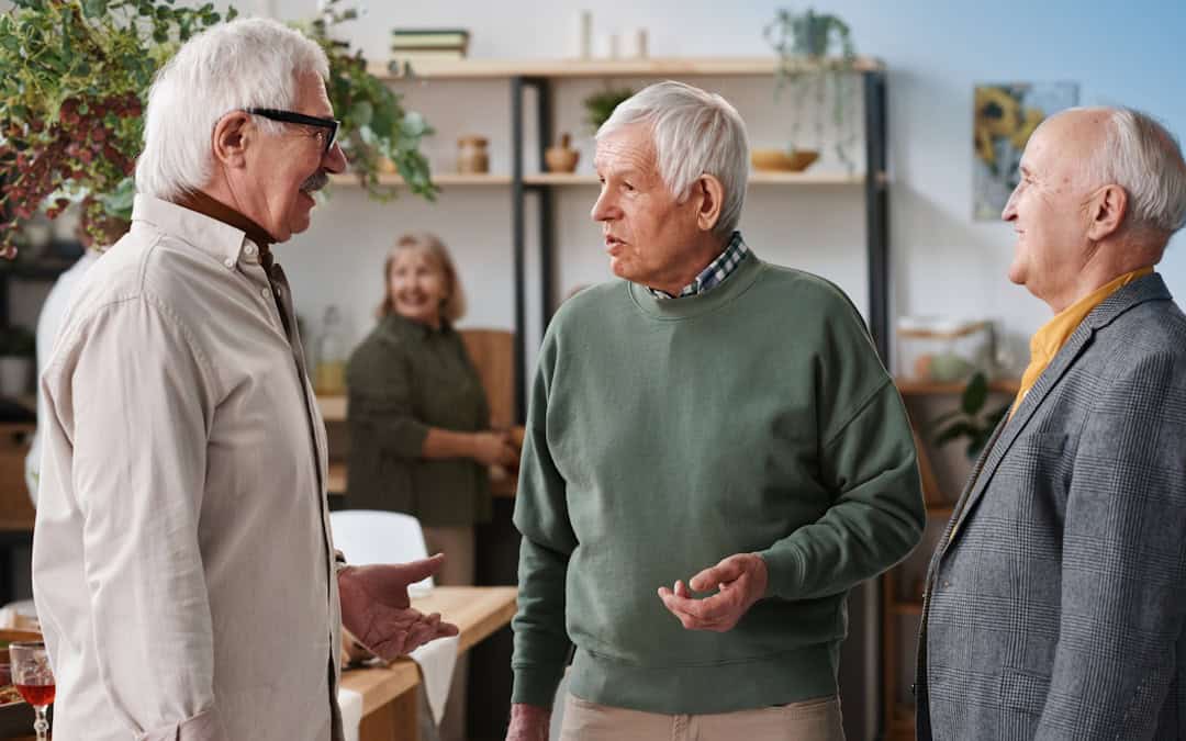 senior-adult-men-socializing-room Three senior adult men socializing in Pittsburgh discussing signs of potential hearing loss.