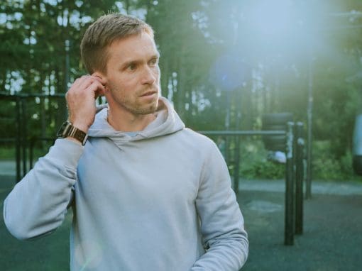 Adult man adjusting earbuds to help protect hearing.